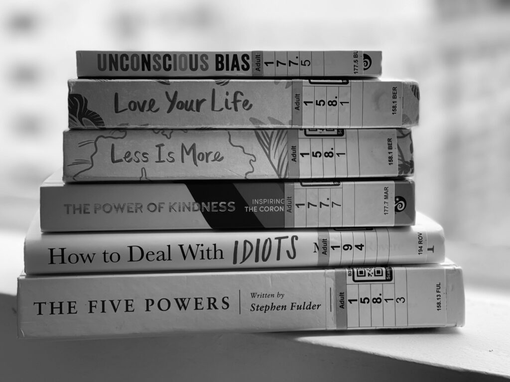 Black and white stack of self-help and inspirational books on a table.